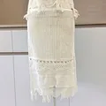 Primo piano di gonna in maglia crochet vintage beige con motivi traforati e frange - Taglia unica / Pantaloni e gonne