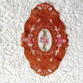 Makroansicht eines vintage ovalen bestickten Spitzen-Untersetzers mit Blumenmuster - 21*14,5 cm / Braun