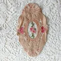 Detailed macro view of vintage beige oval lace coaster featuring delicate pink floral embroidery - 21*14.5cm / Camel