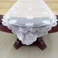 Close-up of white floral lace embroidery on a mesh table runner with scalloped edges. - 130x41cm / White