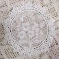 Close-up of white circular organza coaster with intricate floral embroidery details - Style 50 / Diameter 17cm