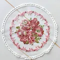 Primo piano dettagliato di una tovaglietta rotonda ricamata con fiori su rete trasparente - Bianco