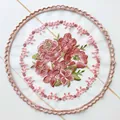 Dettaglio del ricamo floreale su un sottobicchiere rotondo in rete rosa ricamato - Rosa Pasta di Fagioli