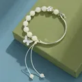 Elegante pulsera de cuentas de bodhi blanco con dije de mariposa plateado sobre caja verde. - Estilo Mariposa