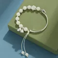 Elegante pulsera de cuentas de Bodhi blancas con dijes de flores plateadas en caja verde. - Estilo Vaina de Semilla de Loto