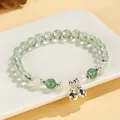 Handcrafted green prehnite beaded bracelet with silver bell charms displayed on white porcelain - Prehnite Moonstone & Green Strawberry Style