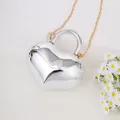 Elegante herzförmige glänzend silberne Mini-Handtasche mit goldener Metallkette. - Silber