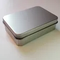 Detail view showing the matte finish of a rectangular silver tinplate metal storage box. - Silver