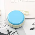 Primo piano di una scatola rotonda blu in latta color macaron per auricolari e monete - Blu lago