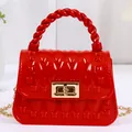 Leuchtend rote Mini-Gelee-Handtasche mit gedrehtem Griff und eleganter goldener Kette. - Rot