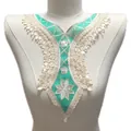 Gros plan d'un col en dentelle brodée turquoise et blanc avec fleurs sur un mannequin - Cyan