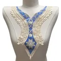 Détail de l'applique d'encolure en dentelle florale brodée beige et bleu sur mannequin - Bleu