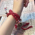 Detail of handmade red braided bracelet with traditional Chinese coin charm on wrist - Red Rope Bracelet / Red
