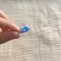 Close-up of cute purple monster ring with big blue eye on fabric background - Purple