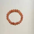 Detailed shot of peach aventurine jade beaded bracelet with elegant mirror reflection - Aventurine Round Beads / Pink Orange
