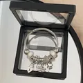 Detailed view of silver charm bracelet with heart, crown, and key pendants in a display box. - Multi-Element Open Bangle / Moonlight White Heart Crown Bracelet