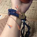 Close-up view of a hand-woven blue braided bracelet with a traditional coin charm. - Green Rope Bracelet / Green