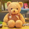Osito de peluche marrón con pelo rizado muy suave y elegante lazo de satén dorado. - Pajarita de alga beige