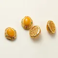 Vue macro détaillée de perles d'espacement florales dorées creuses avec pierres jaunes pour bijoux DIY - Style Ambre et Cire d'Abeille