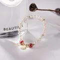 Detailed macro view of handmade freshwater pearl bracelet with red beads and gold charm - Cinnabar Blessing Tag Pearl Style