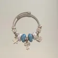 Détail d'un bracelet en acier argenté avec perles bleues et breloques cœur et nœud. - Style Bracelet Jonc / Vert
