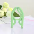 Portable light green folding travel clothes hanger in its compact folded state - Green
