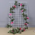 Artificial pink rose vine garland wrapped around a white wire mesh wall grid - Rose Red