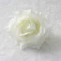 Detailed close-up of a realistic white artificial silk rose flower head on soft fabric - White