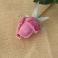 High simulation pink artificial rose bud with realistic petals on burlap background - Purple