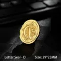 Vintage golden metal wax seal stamp head featuring a decorative ornate letter D design - Letter D
