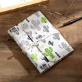 Fabric-covered notebook with cactus print and cord tie on a wooden desk scenery. - Hand-Painted Cactus (NB128) / Large (A5)