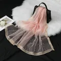 Écharpe élégante en organza rose avec perles et bordure dorée drapée sur un sac noir - Rose