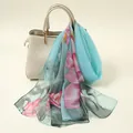 Elegant light blue chiffon scarf with pink floral prints draped on a cream handbag - Floral Print Style (YSY071-2)