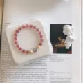Detailed macro shot of a strawberry quartz crystal bracelet with a blue moonstone bead. - Girly Heart Style / Strawberry Quartz Color