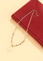 Elegant beaded necklace with carved white crystal pendant on a red vintage book - Aquamarine White Crystal Style