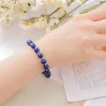 Elegant blue lapis lazuli beaded bracelet with gold spacers shown on woman's wrist - Lapis Lazuli Bracelet