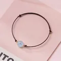Elegant handmade brown cord bracelet featuring a light blue crystal bead and gold accents - Aquamarine - Brown Rope