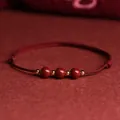 Pulsera artesanal de hilo rojo de cinabrio con tres cuentas y espaciadores dorados - Pulsera rojo vino