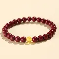 Dark red cinnabar bead bracelet with single translucent yellow amber-colored accent bead - 6mm Purple Cinnabar With Beeswax