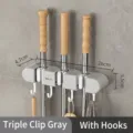 Grey wall-mounted mop and broom holder rack with 3 clips and hooks for home storage. - 三夹装 (26x5.5x4.7cm) / Gray