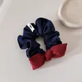 Dettaglio macro di elastico per capelli in denim con fiocco rosso su sfondo neutro - Scrunchie con Fiocco / Rosso