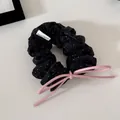 Detail view of a stylish black polka dot scrunchie with a pink leather bow tie - Black Polka Dot - Bow Scrunchie