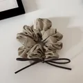 Detail view of a beige polka dot scrunchie with a brown faux leather bow detail. - Green Polka Dot - Bow Scrunchie