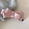 Detaillierte Nahaufnahme einer rosa Satin-Schleife-Banane-Clip auf grauem Pullover. - Cross Bow Banana Clip / Rosa