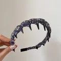 Dettaglio di un cerchietto vintage in tessuto floreale con denti neri per il volume - Stile Pettine / Fiori blu