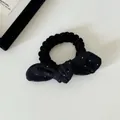Detailopname van een zachte zwarte fluwelen scrunchie met een schattige witte stippenstrik - Strik Haarelastiekje / Zwarte Polkadot