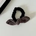 Close-up van een fluwelen scrunchie met een schattige stippen konijnenoren strik. - Strik Haarelastiekje / Koffie met Stippen