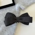 Detailaufnahme einer schwarz-weißen gepunkteten Schleifen-Banane-Haarklammer auf Strick - Bananenspange / Schwarzer Polka Dot