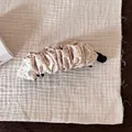 Vue détaillée d'une pince à cheveux banane à pois beige sur un fond de tissu texturé - Pince Banane Plissée à Pois / Beige