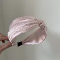 Primo piano di un cerchietto rosa a pois con nodo e trama elegante in raso setoso. - Rosa